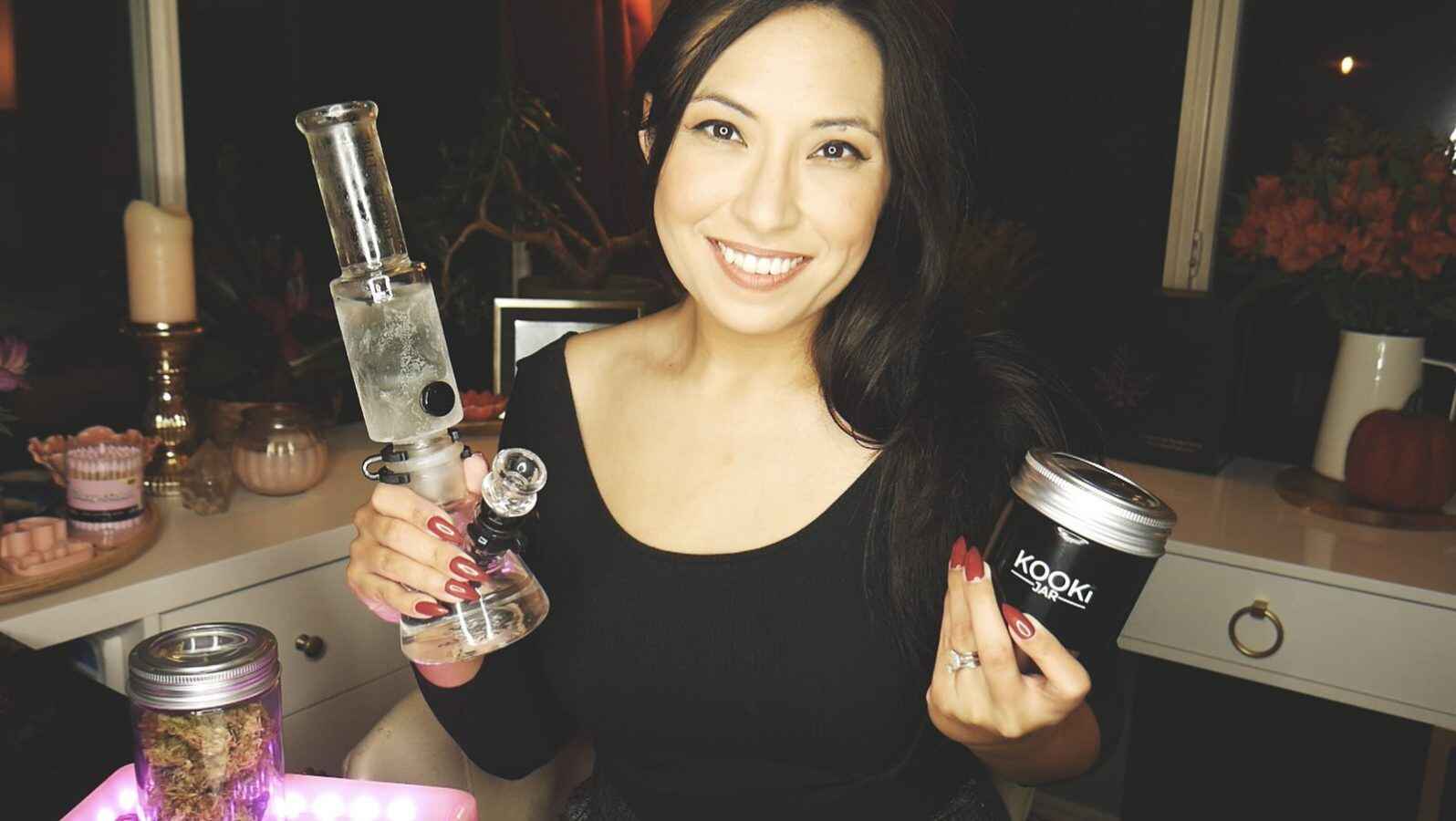 woman holding glass bong and jar of weed